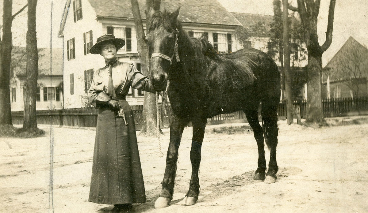 sepia toned photograph of Jennie Powers standing next to a horse